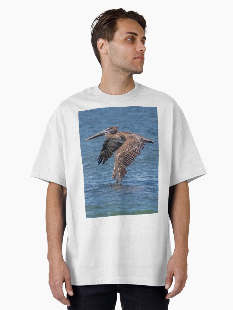 Flying Brown Pelican Touches Water with Wing Oversized T-Shirt | Graphic T-Shirt for Unisex